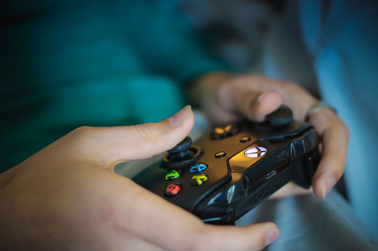 Hands gripping a modern wireless gaming controller indoors. Perfect for tech enthusiasts.